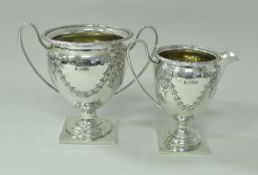 A George V silver cream jug and matching twin handled sugar bowl with swag and bow and harebell