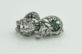 A platinum-mounted emerald and diamond-set brooch in the form of a stylised bow, 3 cm in length, 7.