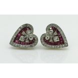 A pair of circa 1900 unmarked yellow metal heart shaped earrings set with rubies and diamonds in