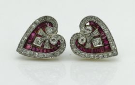 A pair of circa 1900 unmarked yellow metal heart shaped earrings set with rubies and diamonds in