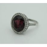 An unmarked 18 carat white gold dress ring set with large rubelite to the centre surrounded by