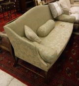 A late George III upholstered camelback sofa on mahogany square moulded supports united to the rear