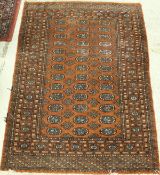 A Bokhara rug the central panel set with repeating elephant foot and tarantula motifs on a rust red