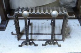 A pair of wrought iron fire dogs with brushed steel finals together with a fire basket