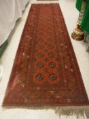 An Afghan runner the central panel set with repeating elephant style medallions on a red ground