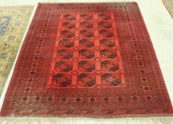 A Bokhara rug the central panel set with repeating medallions on a red ground within a stepped red