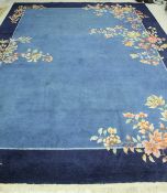 A 1920's Chinese carpet the central panel set with floral sprays on a pale blue ground,