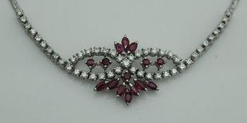 An 18 carat white gold ruby and diamond set necklace in stylised bow and floral spray design,