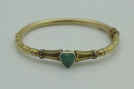 An 18 carat gold bangle set with heart shaped chalcedony stone and flanked by two diamond set