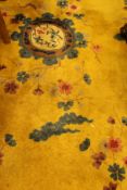 A 1920's Chinese carpet the central panel set with floral decorated roundel on a mustard ground