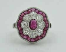 An 18 carat white gold, ruby and diamond set cluster ring in the form of a stylised flower head,