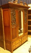 A circa 1900 oak wardrobe with central mirror panel flanked by two carved panelled doors over two