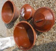 Two large terracotta dough bowls together with two smaller versions with lids