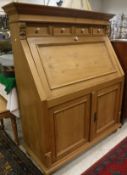 A modern Continental pine bureau with four drawers over a sloping fall and two cupboard doors and a