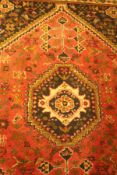 A Shiraz rug the central panel set with lozenge shaped medallion with a red floral decorated ground