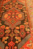 A Persian rug the central panel set with lozenge shaped medallion on red ground with a stepped blue