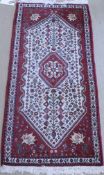 A Persian rug the central panel set with floral decorated medallion on a cream and red ground