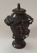 A Japanese chocolate patinated bronze vase decorated in high relief with grape and vine,