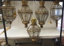 A collection of five patinated beaten tin and glazed ceiling lanterns, probably Spanish,