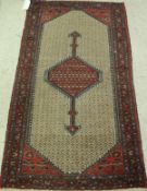 A Hamadan rug the central panel set with red medallion in a fawn ground lozenge panel within a red,