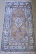 A eastern rug the central panel set with lozenge shaped medallion on a mushroom ground with