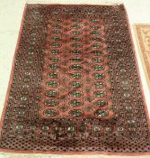 A Bokhara rug the central panel set with repeating elephant foot and tarantula medallions on a pink