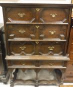 An early 20th Century oak chest on stand in the Jacobean manner with three long over two short