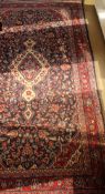 A Persian rug, the central panel set with floral decorated medallion on a dark blue floral ground,