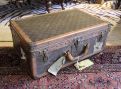 A Louis Vuitton suitcase with monogram print exterior, brass and leather trim,