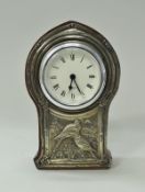 An Edwardian silver sheathed decorated clock case with embossed decoration depicting birds amongst