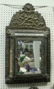 A 19th Century style Dutch cushion mirror with embossed metal decoration the centre plate door