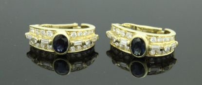 A pair of 18 carat gold earrings set with central oval sapphires and baguette and brilliant cut