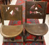 Two similar tribal carved hardwood chairs with pierced backs and demi-lune adzed seats,