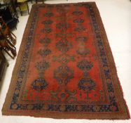 A Turkish carpet the central panel set with all over scrolling motifs on a red ground within a