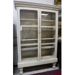 A painted pine cabinet with two glazed doors enclosing four shelves,