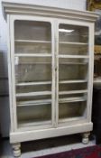 A painted pine cabinet with two glazed doors enclosing four shelves,