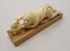 A circa 1900 Celonese carved ivory figure as a boy crawling and taking a peach from a bowl of