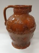 An over-sized brown glazed terracotta harvest type jug with Bacchus mask spout and grape and vine