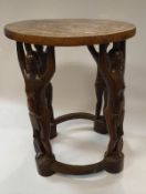 A West African carved hard wood table as four loin clothed figures holding aloft the table top