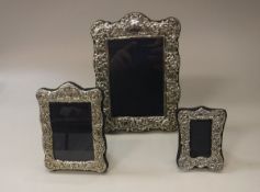 Three modern silver photo frames in the Edwardian manner each housed on blue velvet,