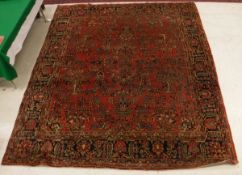 A Persian carpet the central panel set with all over floral sprays on a red ground within a red,