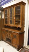 A late Victorian oak dresser with glazed upper section on a base of three drawers and recess