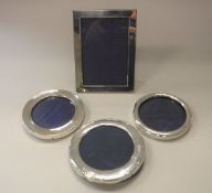 A modern silver photo frame of plain rectangular form together with three circular examples