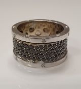 A large modern platinum ring set with white diamonds on the outside edges and a revolving centre