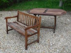 A stained slatted teak bench and similar garden table