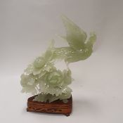 A 20th Century carved jade figure of a phoenix amongst flowers on a carved wooden stand