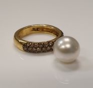 An 18 carat gold ring set with diamonds and an articulated pearl.