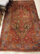 A Caucasian rug the central panel set with lozenge shaped medallion on a dark red stylised floral