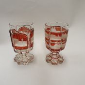A pair of late 19th Century Bohemian ruby overlaid glass goblets each depicting various grand
