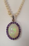 A large white gold set opal pendant surrounded by amethysts mounted on a pearl necklace with silver